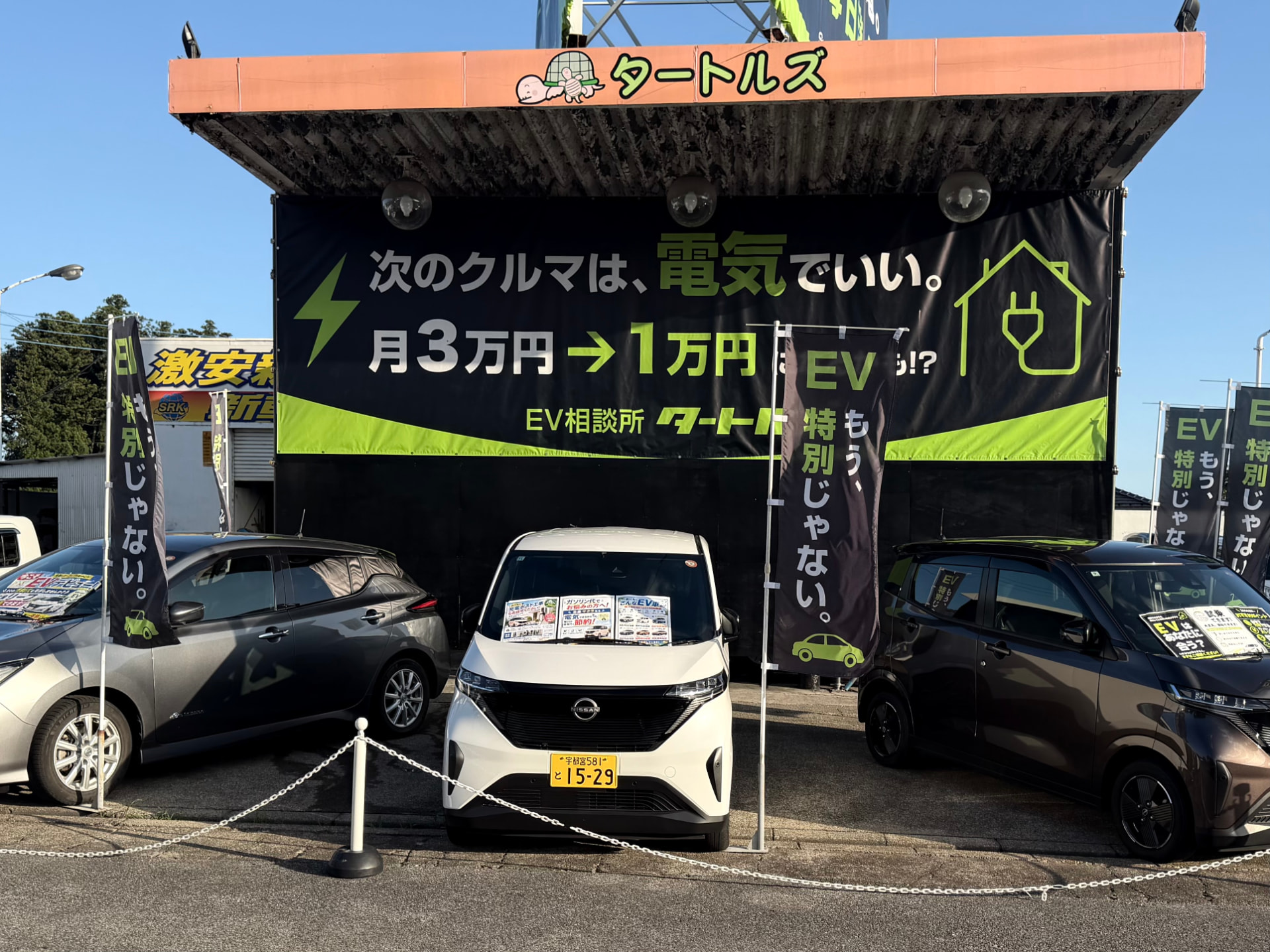 EV相談所タートルズの店舗外観。3台のEVが並び、オレンジとグリーンの看板が見える